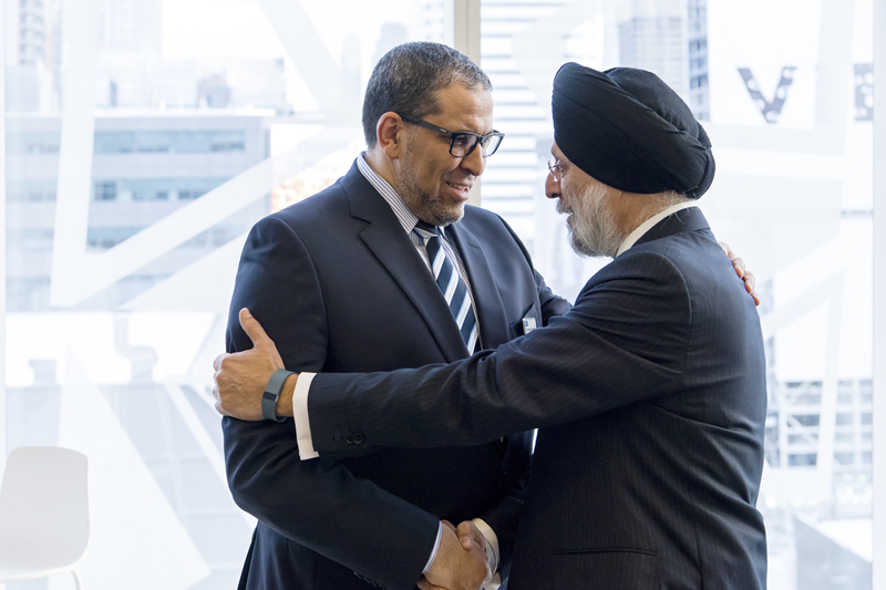 Mohamed Lachemi at the SLC shaking hands with a elder man who is South Asian wearing a turban.